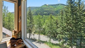A room with a large window overlooking a forested mountain area. - Gore Range Retreat I Mountain Views & Adventure (Vail)