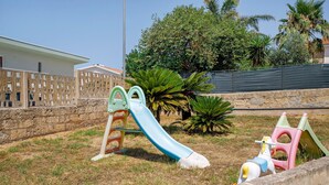 A playground with a slide and climbing structures, surrounded by a stone wall and greenery. - 'Dimora Del Principe' with Sea View, Wi-Fi and Air Conditioning (Principe)