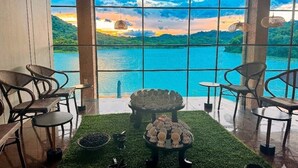 Habitación con vista a un lago, amoblada con sillas y una mesa, y un centro decorativo.