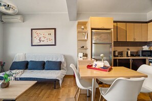 Ein gemütlicher Wohnbereich mit einer Couch, einem Esstisch und einer Küchenzeile.