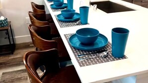 Eine moderne Küche mit weißer Arbeitsplatte, blauem Geschirr und Holzstühlen.