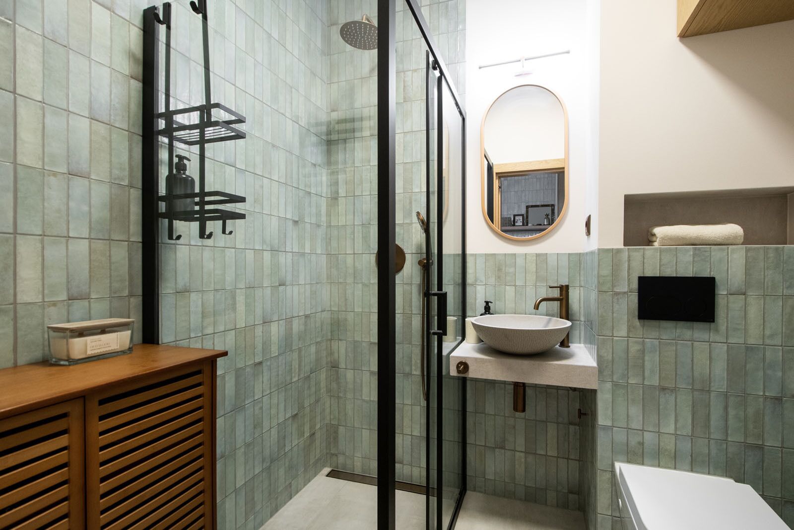 A bathroom with a glass-enclosed shower, a white sink, and a wooden vanity.
