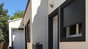 Un bâtiment moderne à l’extérieur blanc, doté de fenêtres à encadrement noir et d’un escalier menant à une porte.