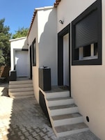 Un edificio moderno con fachada blanca, ventanas de marco negro y una escalera que lleva a una puerta.