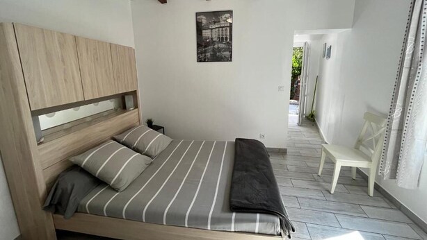 Une chambre à coucher avec un lit, une tête de lit en bois, un banc et un tableau encadré accroché au mur.