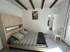 Un dormitorio con una cama, cabecera de madera, un banco y un cuadro enmarcado en la pared.