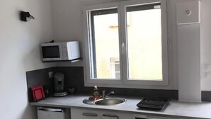 Une cuisine compacte équipée d’un four à micro-ondes, d’un évier et d’un petit réfrigérateur.