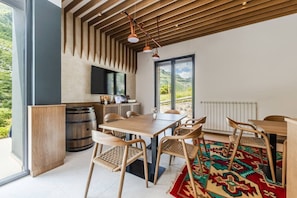 Ein moderner Essbereich mit einem Holztisch und Stühlen, einem großen Fenster mit Blick auf Grünflächen und einem gemusterten Teppich.
