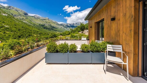 Un balcone con vista sulle montagne, una parete in legno e una sedia bianca.