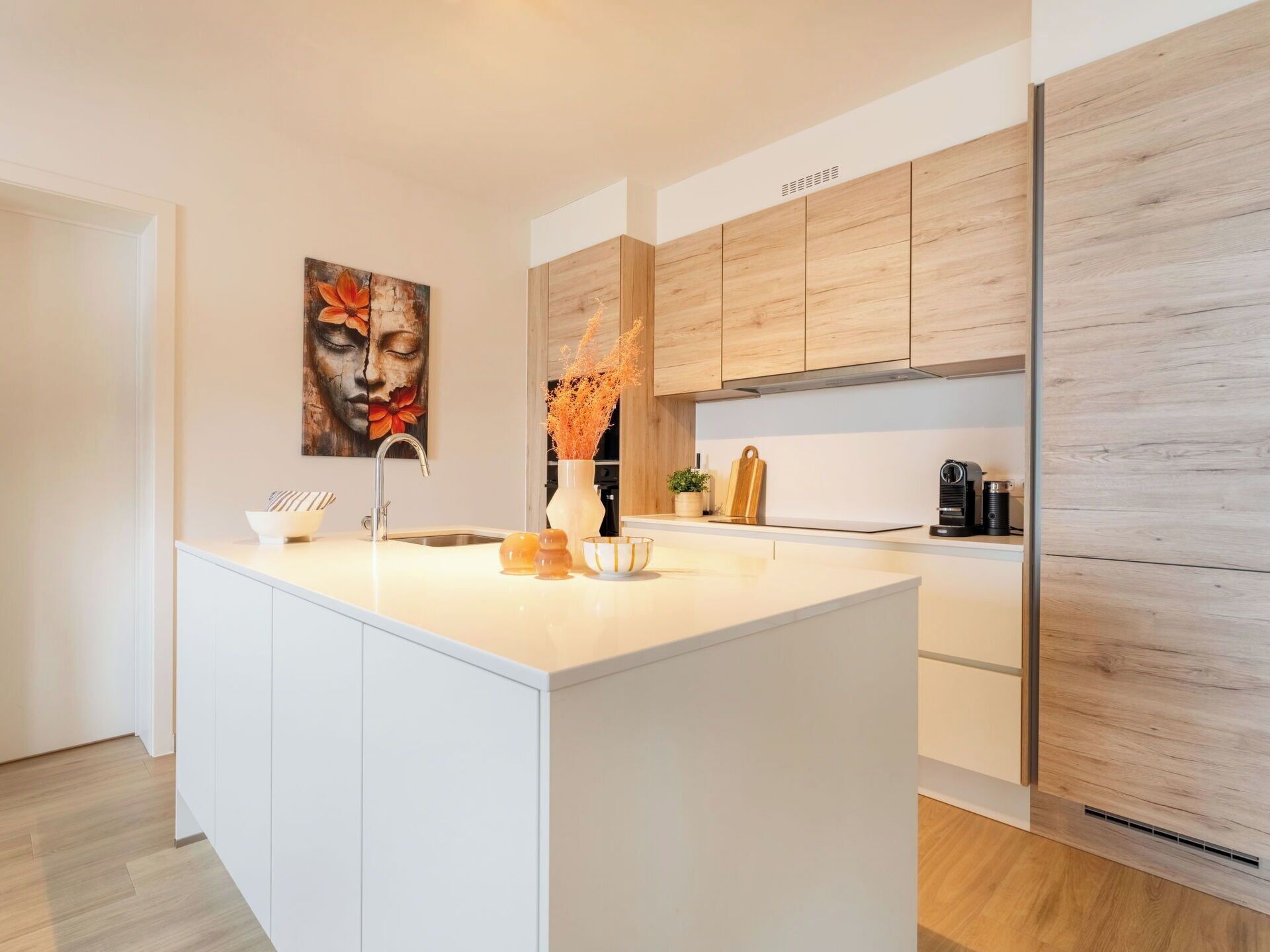 Una cocina moderna con una isla central, armarios blancos y una pared de acento de madera.