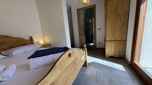 Un dormitorio con cama de madera, una mesita de noche, una lámpara y vistas a través de una ventana.