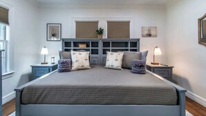A bedroom with a large bed, two bedside tables, a headboard, and a built-in shelving unit. - Bayfront Breeze on Ocean Drive Sleeps 15 (Corpus Christi)