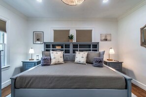 Ein Schlafzimmer mit einem großen Bett, zwei Nachttischen, einem Kopfteil und einer eingebauten Regaleinrichtung.