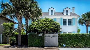 A two-story house with a gated entrance, surrounded by palm trees and a hedge. - Bayfront Breeze on Ocean Drive Sleeps 15 (Corpus Christi)