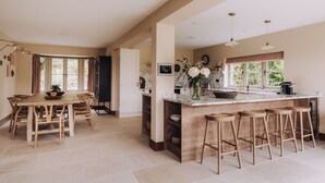 A spacious kitchen with a marble countertop, wooden stools, and a large window. - Moss Ghyll | Hot Tub, Sauna & Cinema Room (Windermere)