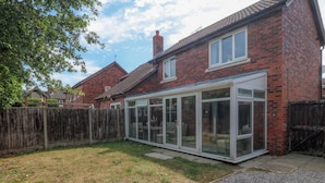 A house with a conservatory, a wooden fence, and a gravel driveway. - Robins Nest (Rhyl)