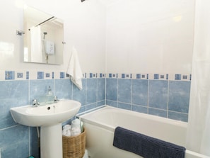A bathroom with a sink, mirror, and bathtub. - Robins Nest (Rhyl)