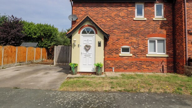 A two-story brick house with a white front door, a small window, and a satellite dish. - Robins Nest (Rhyl)