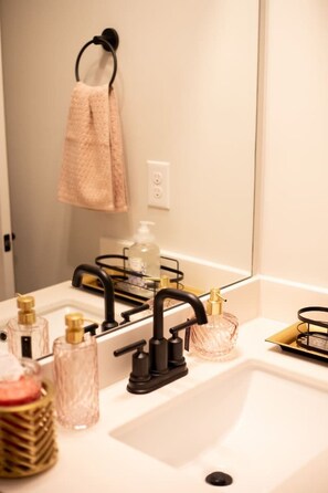 A bathroom with a white sink, black faucet, and various toiletries. - Five-minute walk to downtown Atlanta with Rooftop (Atlanta)