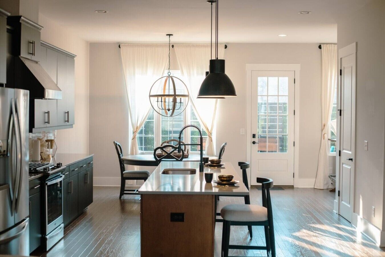 A modern kitchen with a central island, stainless steel appliances, and pendant lighting.