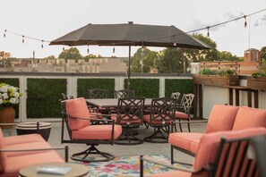 A rooftop patio with a table and chairs, an umbrella, and string lights. - Five-minute walk to downtown Atlanta with Rooftop (Atlanta)