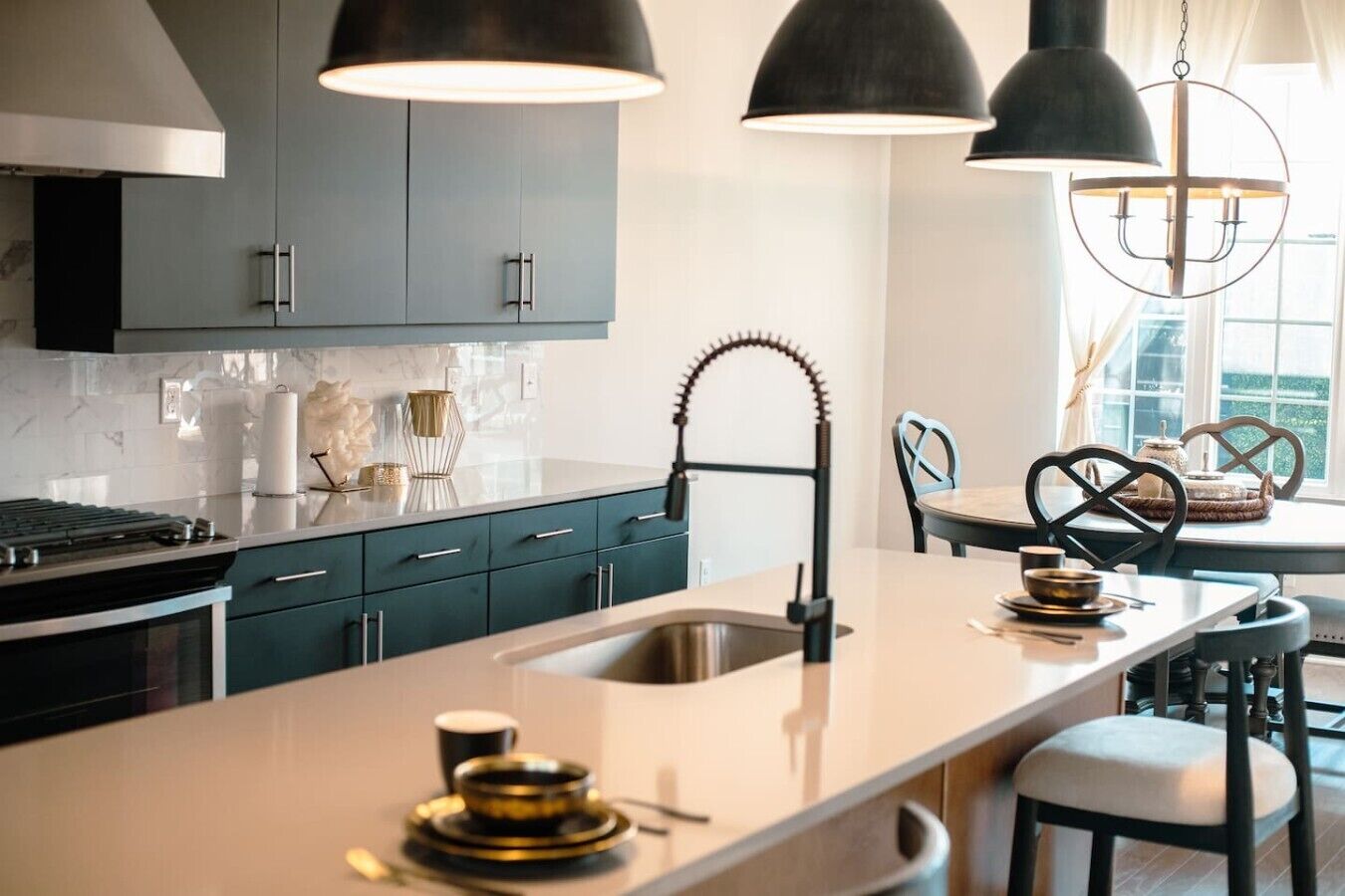 A modern kitchen with dark cabinets, a central island, pendant lighting, and a view of the dining area.