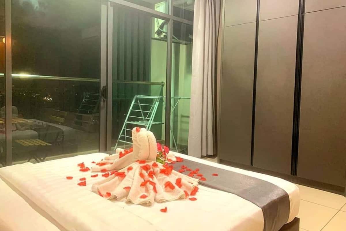 A hotel room with a bed, a view of the outside, and a balcony with chairs.