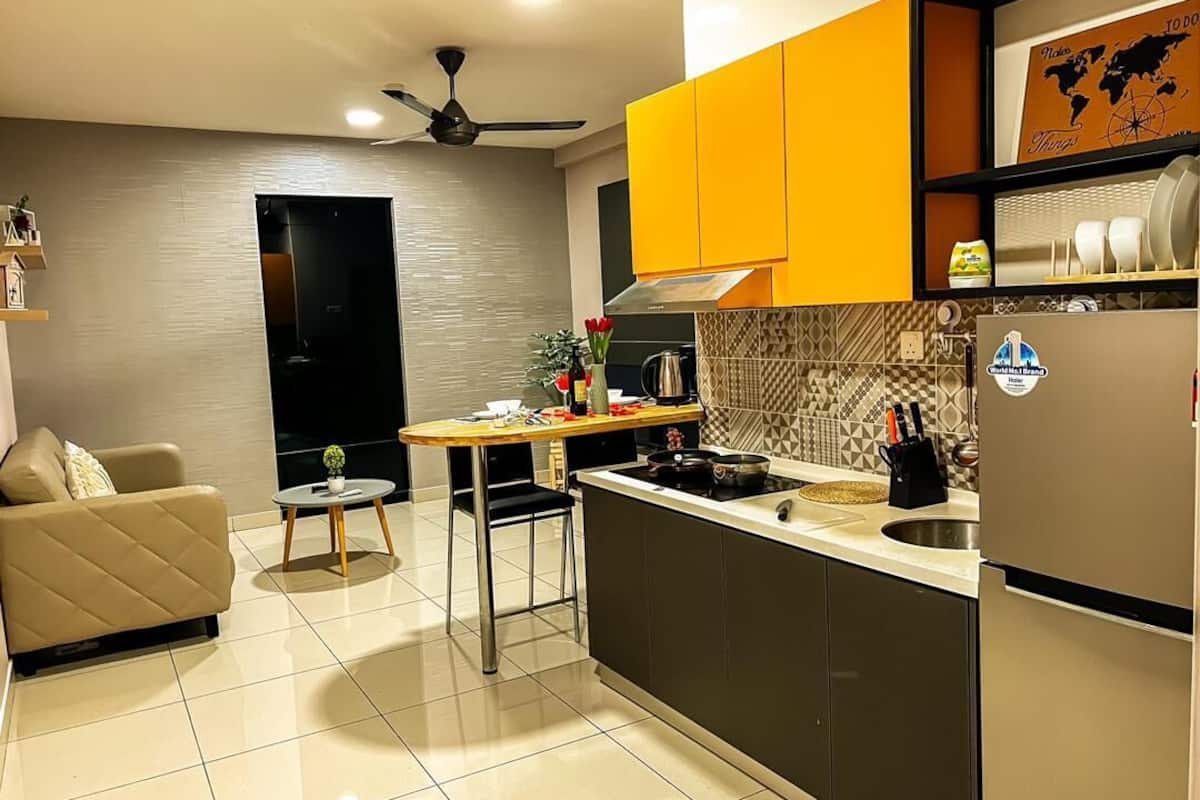 A modern kitchen with a dining area, a sofa, and a ceiling fan.
