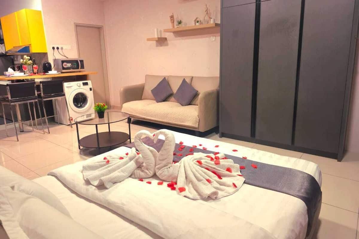 A hotel room with a bed, a sofa, a washing machine, a desk, and a wardrobe.
