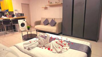 A hotel room with a bed, a sofa, a washing machine, a desk, and a wardrobe.