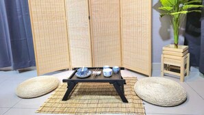 Una habitación con esteras de tatami, una mesa baja con cuencos, palillos y una planta en maceta.
