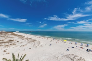 A beach with a pier extending into the water, sandy beach, and clear skies. - Surfside on the Beach (Gulf Shores)
