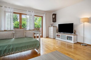 A bedroom with a bed, a TV, a dresser, and a window with curtains.