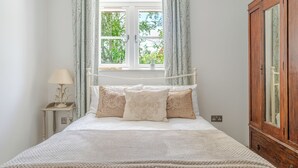 Un dormitorio con cama, mesita de noche, ventana con cortinas y armario de madera.