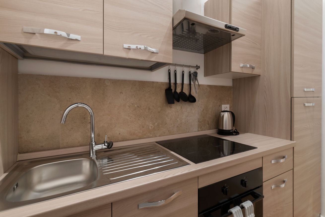 A modern kitchen with a stainless steel sink, a stovetop, and a coffee maker.