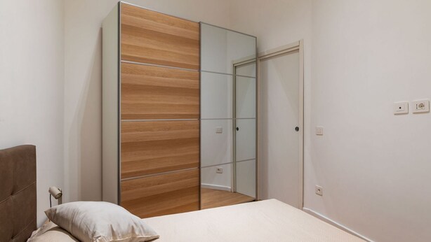 Un dormitorio con una cama, un armario de madera y un espejo.