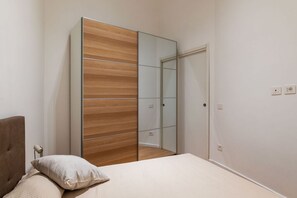 Ein Schlafzimmer mit einem Bett, einem Holzschrank und einem Spiegel.