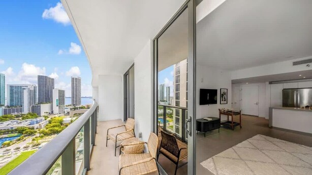 A modern apartment with a balcony, a kitchen, and a dining area. - High-Rise One-Bedroom Condo In Edgewater Miami (Miami)