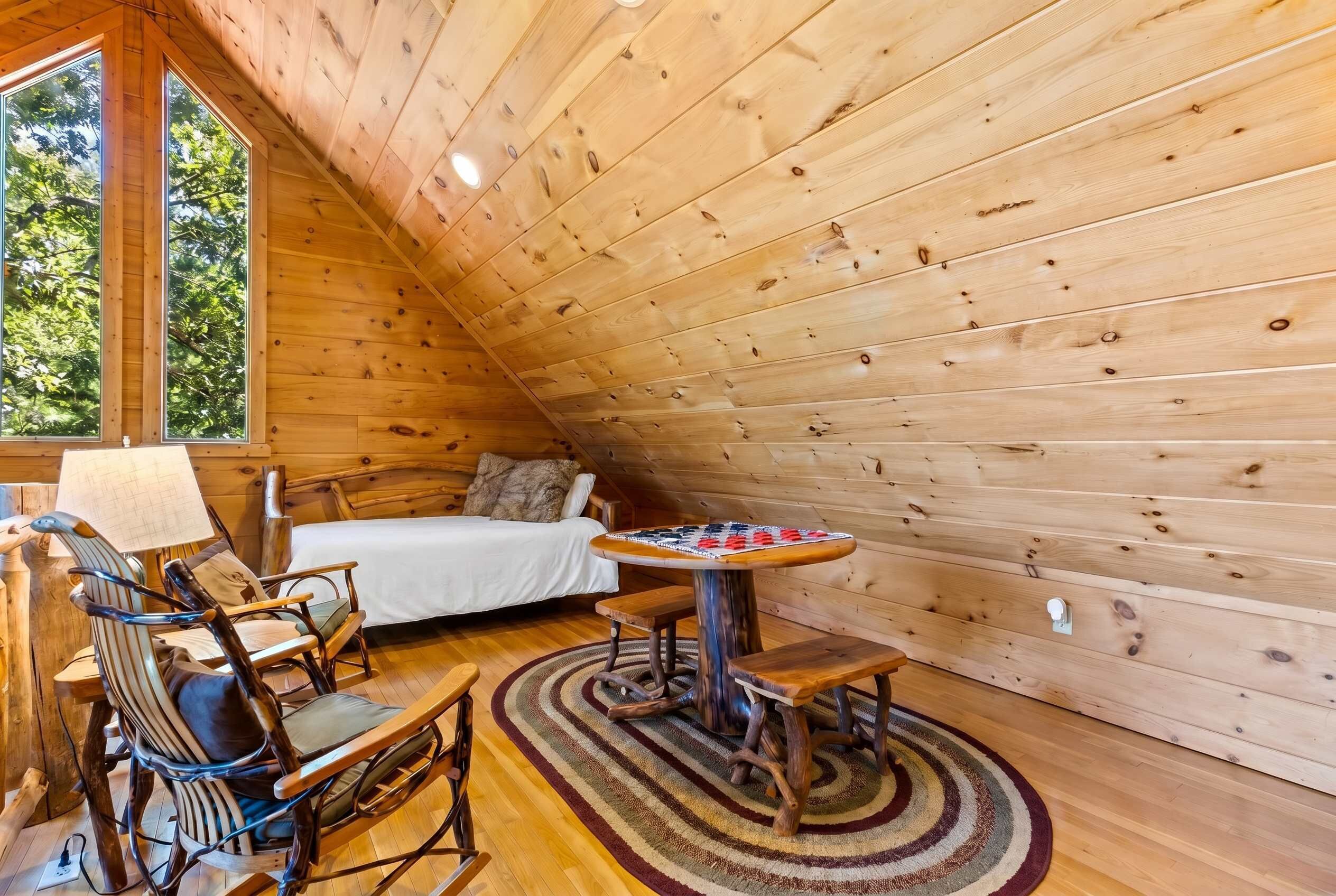 L’intérieur d’un chalet en bois chaleureux et accueillant, avec un lit, une table à manger et une cheminée.