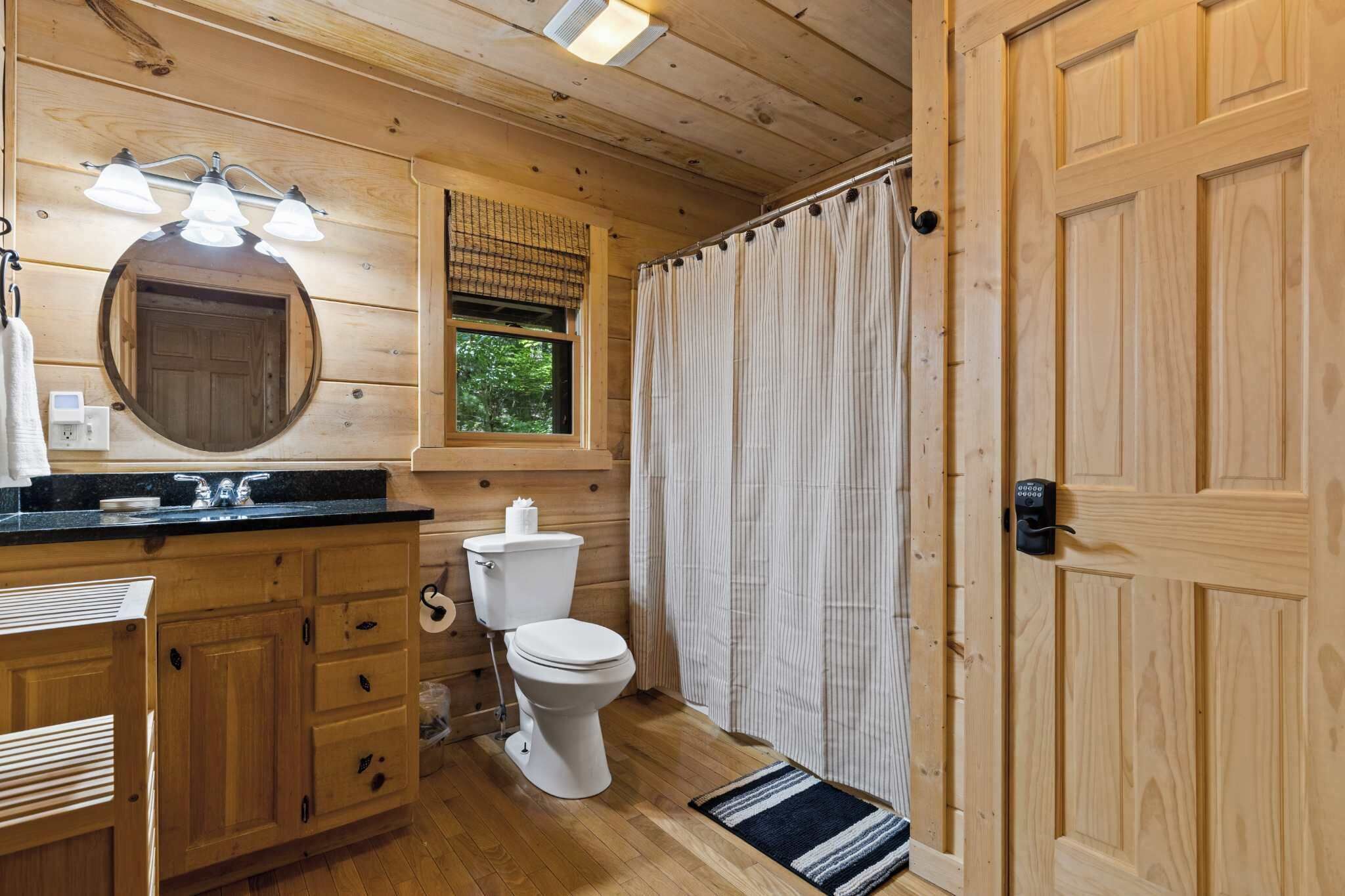 A wooden cabin bathroom with a sink, toilet, and a shower curtain.