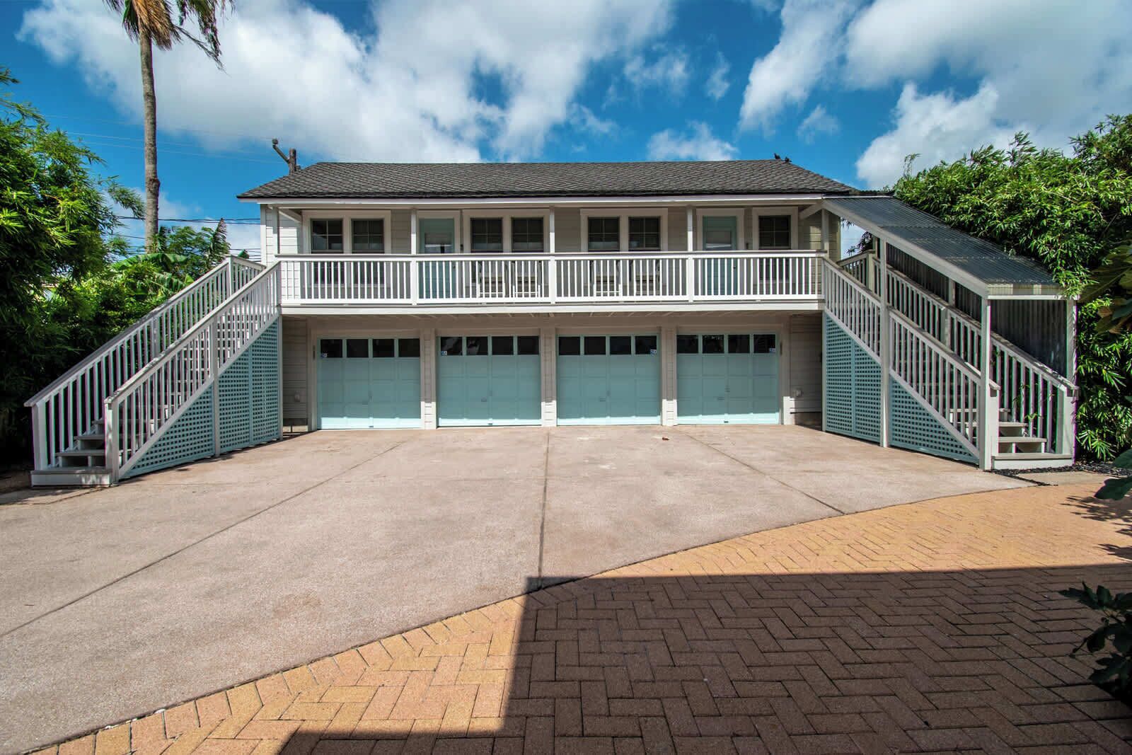 A two-story building with a balcony, a covered parking area, and a staircase on each side.