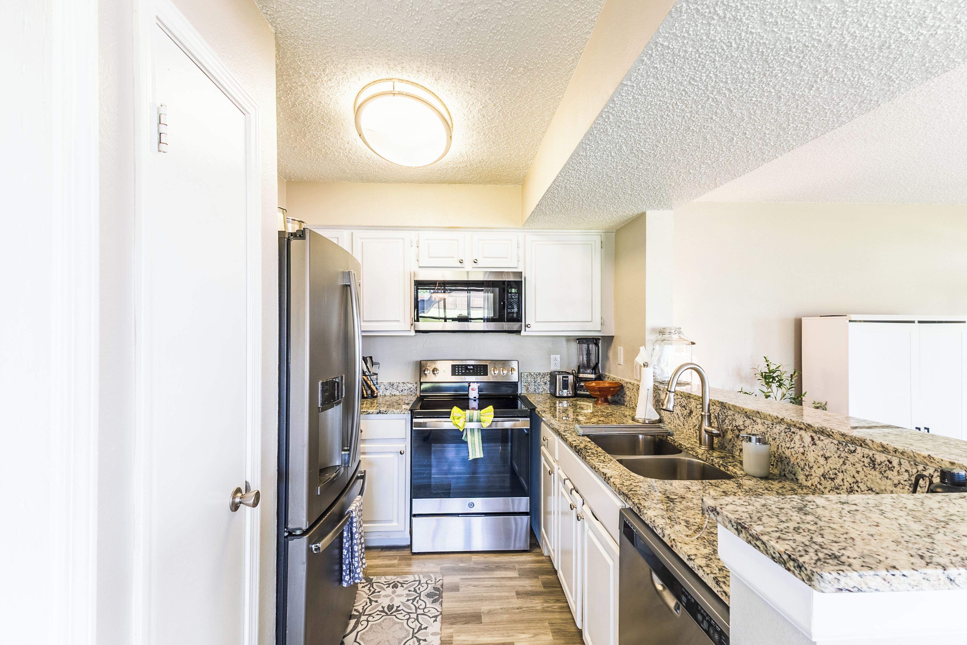 A modern kitchen with stainless steel appliances, granite countertops, and white cabinetry.
