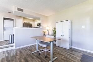 A compact kitchen with modern appliances, a dining area with a table and chairs, and a small trash bin.