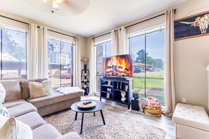 A living room with a sofa, a coffee table, a TV, and a fireplace.