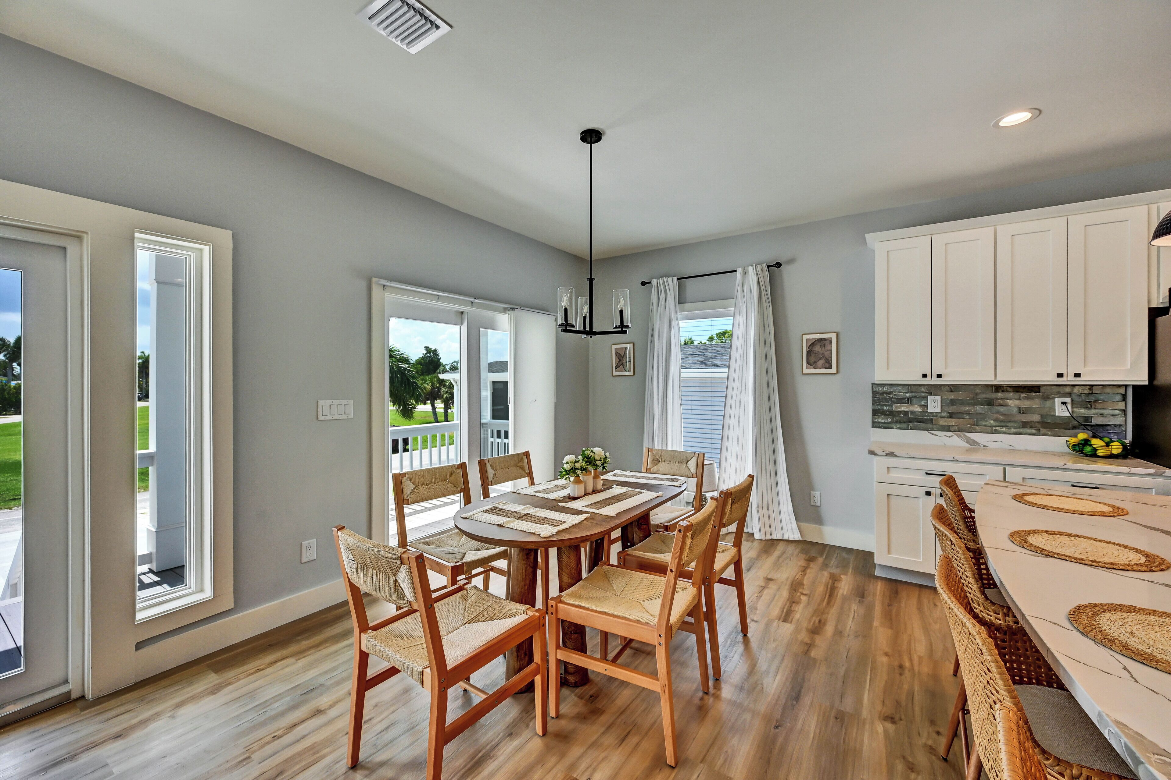A spacious kitchen with a dining area, wooden flooring, and white cabinetry.