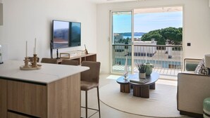 Una sala de estar moderna con comedor, televisor y balcón con vista a la ciudad.