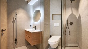 Un baño moderno con tocador de madera, inodoro y zona de ducha.