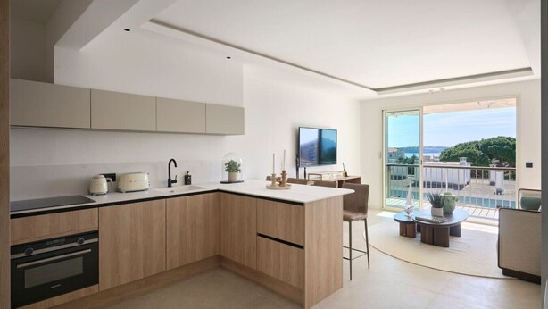 Una cocina moderna con horno integrado, un comedor con mesa de vidrio y un balcón con vistas.