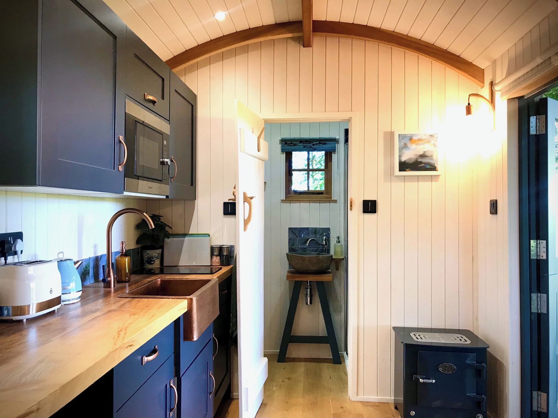 A kitchen with a wooden countertop, a sink, a stove, and cabinets.