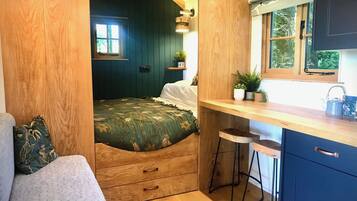 A compact room with a bed, a small kitchenette, and a window.